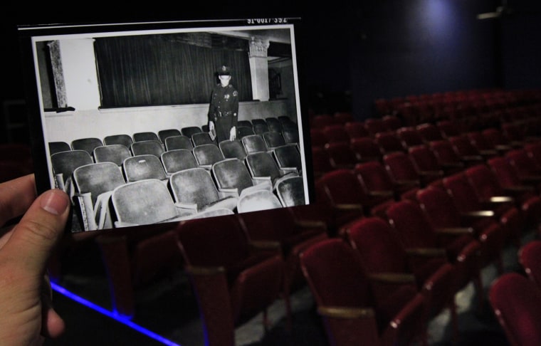 Dallas police officer points to the seat at the Texas Theater where Lee Harvey Oswald was sitting on Nov. 22, when police entered to arrest him, juxtaposed against the current scene in Dallas.