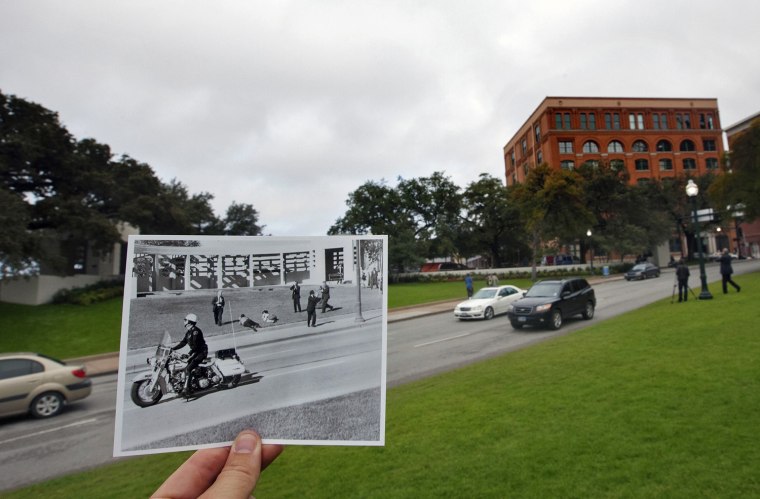 Spectators lie on the ground in Dealey Plaza as a motorcycle police officer drives by immediately after the shooting of John F Kennedy on Nov. 22, 1963, juxtaposed outside of the current day Elm Street, in Dallas.