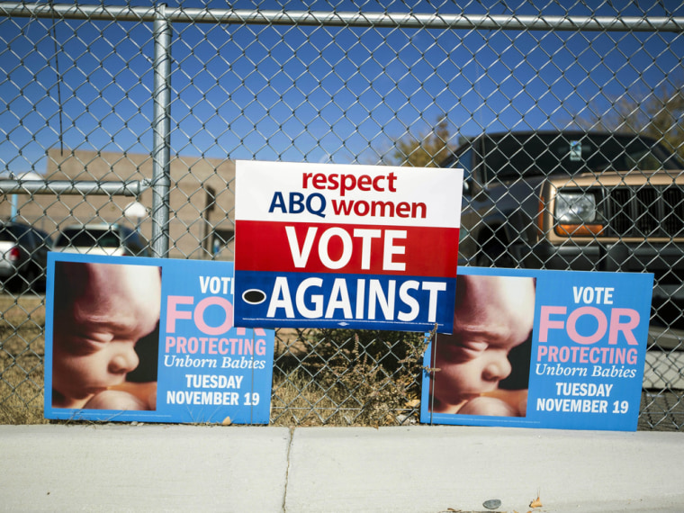 Signs advocating for and against a late term abortion ban hang on a fence outside of a voting site at Eisenhower Middle School in Albuquerque, N.M., on Nov. 19.