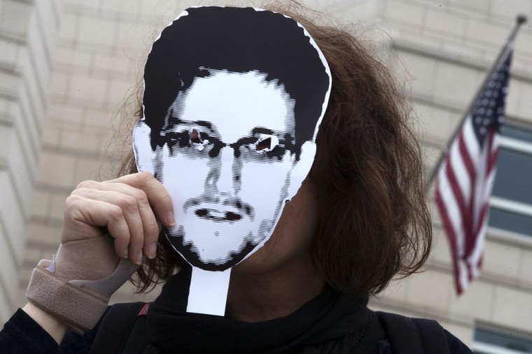 A woman holds a portrait of former U.S. spy agency contractor Edward Snowden in front of her face as she stands in front of the U.S. embassy during a protest in Berlin, July 4.