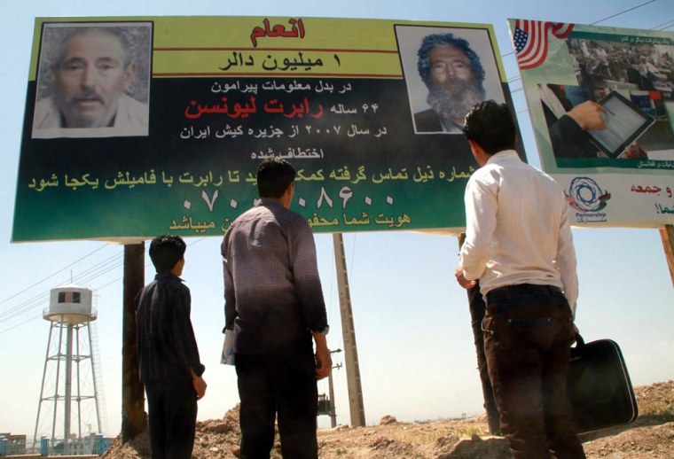 Afghans look at a billboard promising a reward for information leading to the recovery of former FBI agent Robert Levinson, in Herat, near the Iranian border, on April 24, 2012.