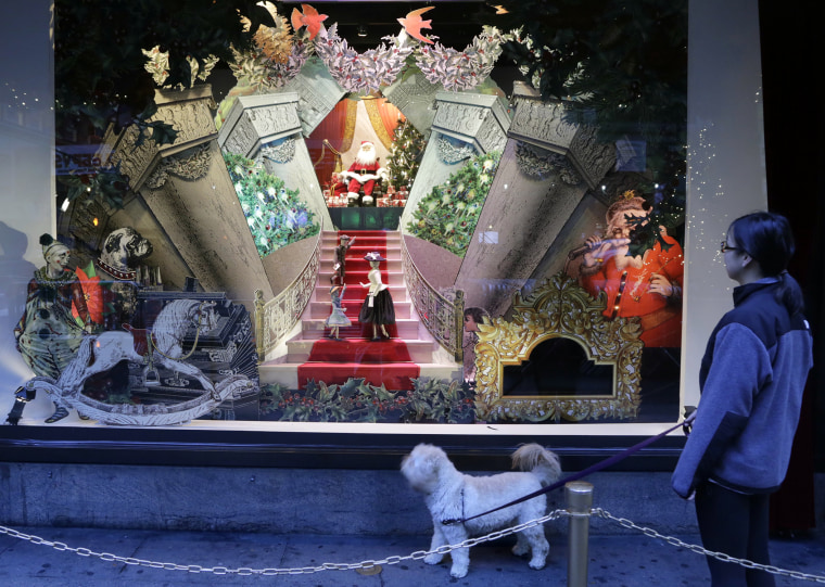 A woman walking her dog past a vintage Santa Claus holiday window display at Lord & Taylor department store in New York. 