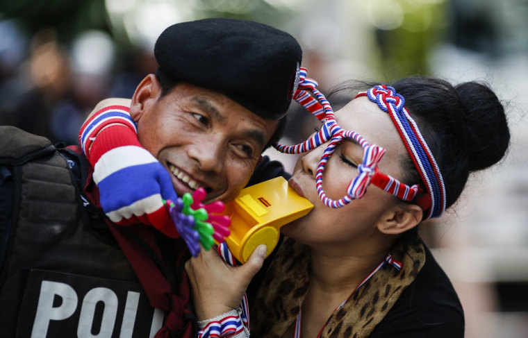 An anti-government protester blows a whistle next to a riot policeman as she gathers with others outside the headquarters of the Prime Minister Yingluck Shinawatra's ruling party in Bangkok, Thailand, on Friday.