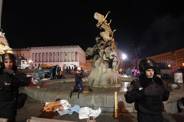 Riot police stand guard as utility workers clean up Independence Square after a protest in Kiev on Nov. 30, 2013.