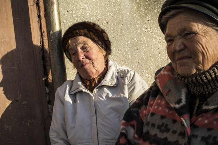 Two women sit outside their apartment building in Baikalsk, Russia.