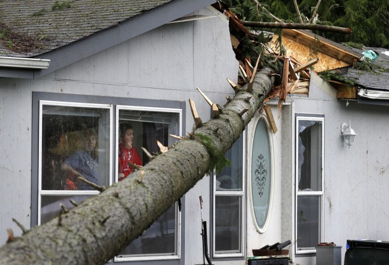 Mary Hursh, left, and Catarina Schulte, right, look out the window of their home in the Frederickson neighborhood near Puyallup, Wash., at a tree that fell on their roof after a tornado moved through the area earlier in the day on Sept. 30.