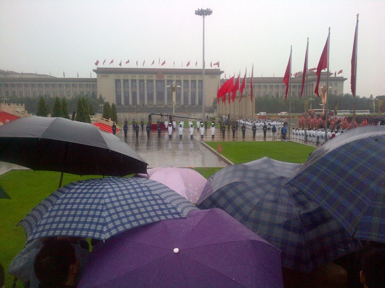 Journalists huddled under umbrellas watch China's National Day celebrations. The rest of Tiananmen Square was almost deserted.
