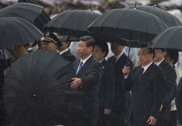 Chinese President Xi Jinping, center, opens his umbrella as Premier Li Keqiang, right, and Chinese Communist Party top leaders stand in the rain after bowing before the Monument to the People's Heroes during a ceremony marking National Day at Tiananmen Square in Beijing on Tuesday.