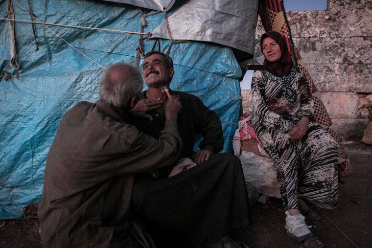 Displaced Syrian men shave as a woman watches near Kafer Rouma, on Sept. 26.