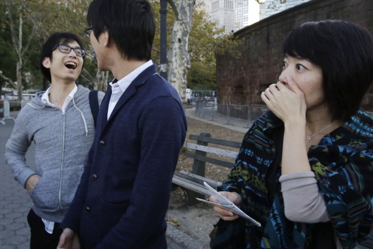Tourist Tomoko Ida, right, of Tokyo, covers her mouth when she hears that the Statue of Liberty is closed, Oct. 1, in New York City. Traveling with her are Jin Onuki, left, and Tomoya Osada.