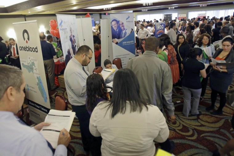 Job seekers check out companies at a job fair in Miami Lakes, Fla. A private survey says hiring remained essentially slow and steady in September.
