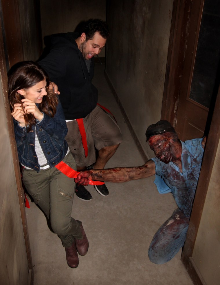 An actor portraying a zombie grabs a flag from the belt of someone walking through the Prison of the Dead Escape, part of the Shocktoberfest attraction in Reading, Pa.