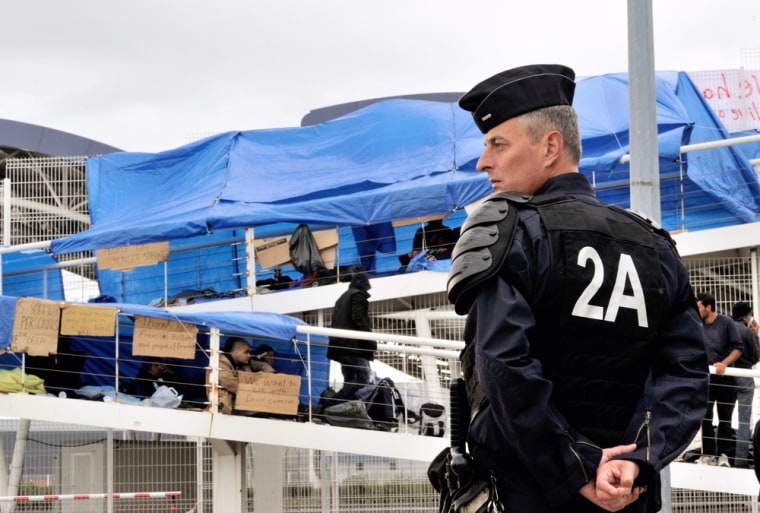 A policeman stands guard Friday near Syrian refugees occupying the footbridge of a ferry terminal in Calais.