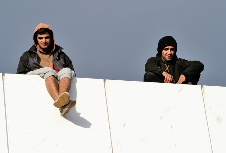 Two Syrian refugees sit on a roof at the ferry terminal at Calais.