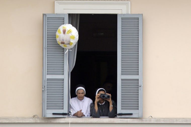 A nun uses binoculars to watch Pope Francis as he leads a Mass in front of St. Francis Basilica.