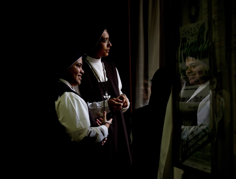Nuns look at Pope Francis leaving the Archbishop's residence in Assisi.