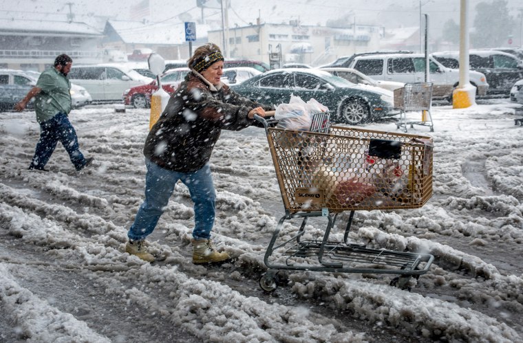 Brenda Nolting rolls her cart through heavy slush and snow after stocking up on necessities Friday at a supermarket in Rapid City, S.D. Winter Storm Atlas dumped up to three and a half feet of wet, heavy snow on parts of South Dakota.