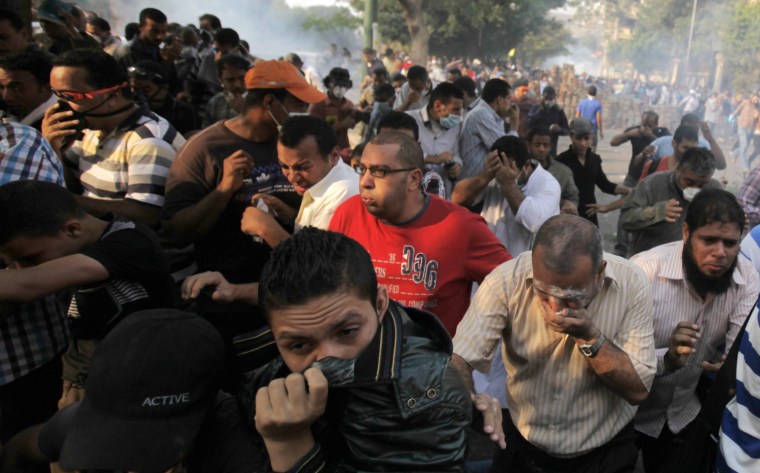 Members of the Muslim Brotherhood and supporters of ousted Egyptian President Mohamed Morsi run from tear gas released by riot police during clashes in Cairo on October 6, 2013.