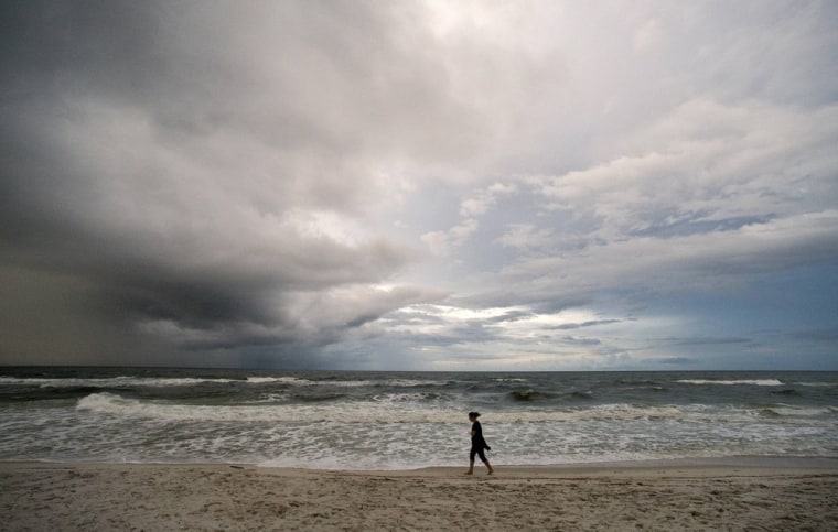 A beachgoer takes an early morning walk as storm clouds from a weakening Tropical Depression Karen approach Orange Beach, Alabama, on Oct. 6.