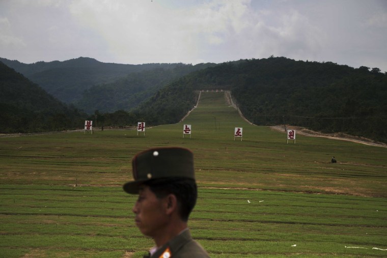 A soldier passes by a ski slope under construction at North Korea's Masik Pass. The signs on the slope read