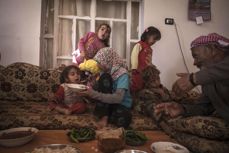 Mohammed Kale, right, the family patriarch, sits with his grandchildren as they eat lunch.