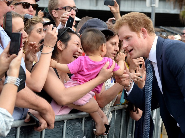 epa03896991 Prince Harry (R) jokes with a toddler as he is greeted by a large crowd during the International Fleet Review in Sydney, Australia, 05 Oct...