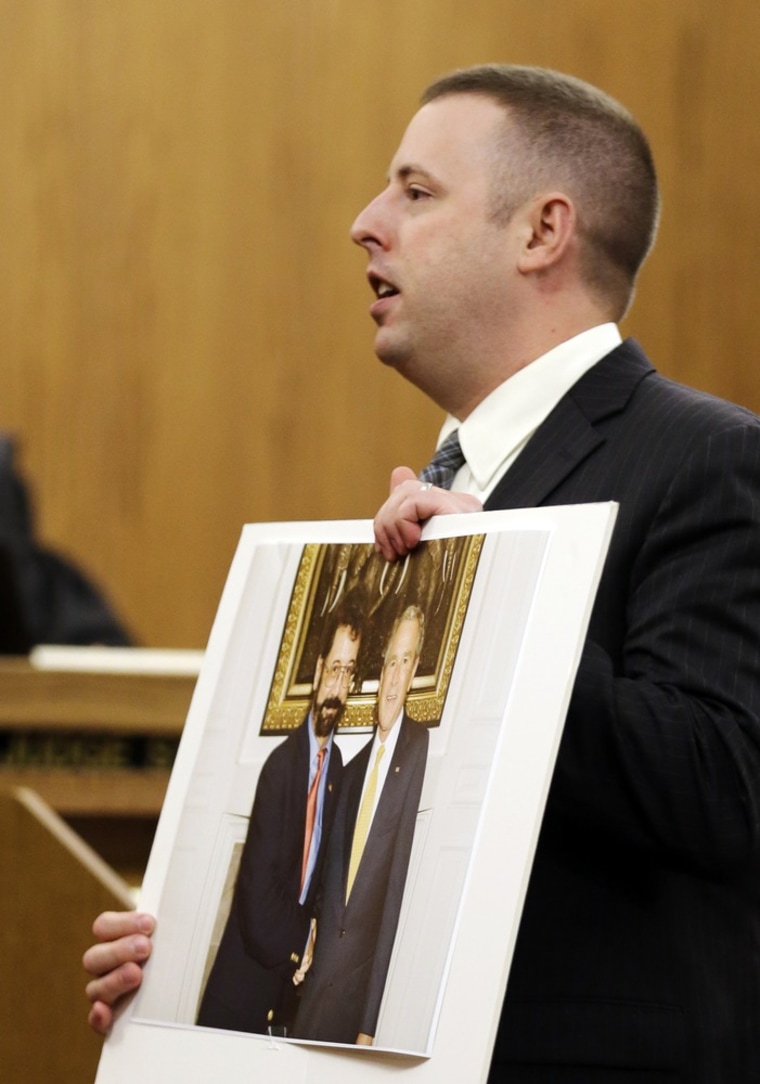Defense attorney Joseph Patituce holds photos of a man who calls himself Bobby Thompson with then President George W. Bush during opening arguments in Thompson's fraud case in Cleveland, Monday.
