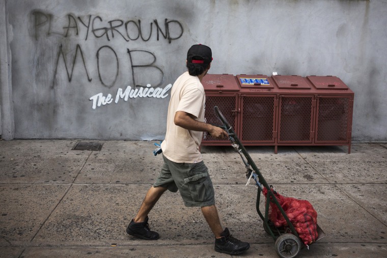 A pedestrian looks toward street art reading,