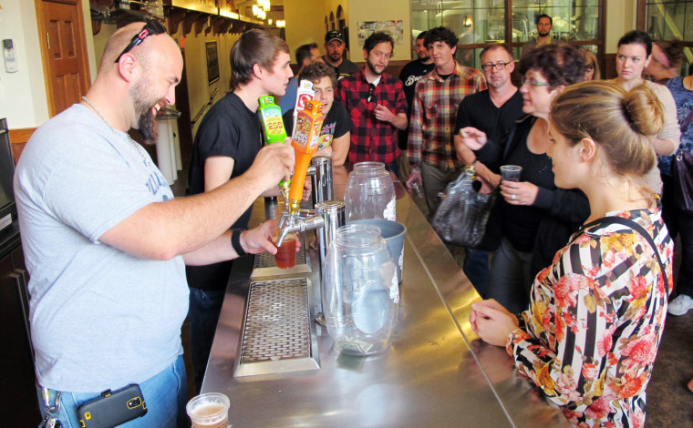 In this Oct. 3, 2013 photo, Mark Paprocki, left, and Dylan Maz pour beer during a tour at Lakefront Brewery in Milwaukee. The federal government shutd...
