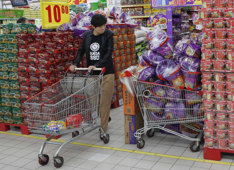 A woman looks at Tingyi's instant noodles, which is packed with a plastic bucket giveway, at a supermarket in Beijing. A price war for China's $8.8 billion instant noodle market, sparked last year by Uni-President China Holdings Ltd's sausage giveaways, soon escalated into other gifts.