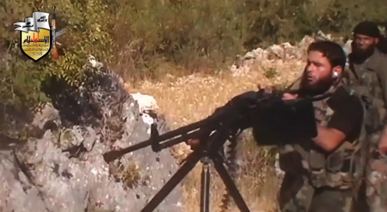 A rebel fighter fires a gun in a valley in an unidentified location in Latakia province on Aug. 11.