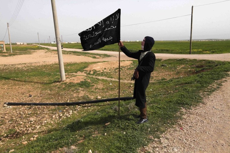 A fighter from Islamist Syrian rebel group Jabhat al-Nusra holds an Islamist flag in Raqqa province, eastern Syria, in this March 12, 2013 file photo.