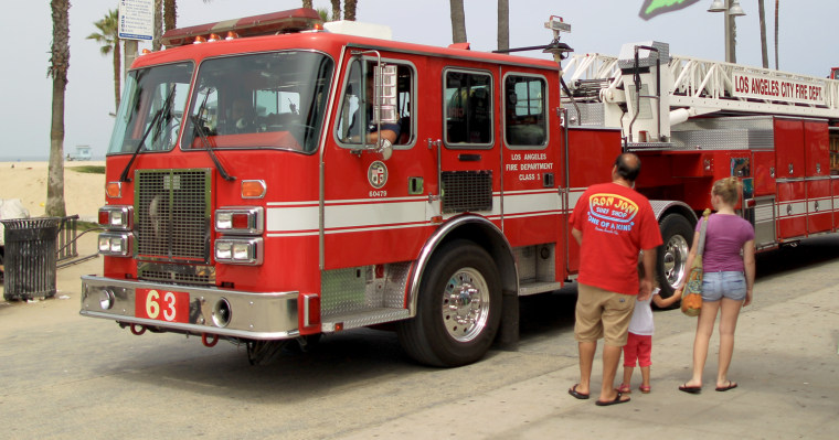 VENICE, CA - JULY 6: A family watches a firetruck pass a business on the boardwalk that certifies people to smoke medical marijuana with $40 evaluati...