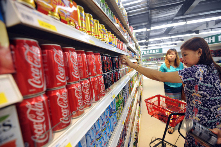 A Myanmar woman takes a can of Coca-Cola from a shelf at a supermarket in Yangon, the capital city.