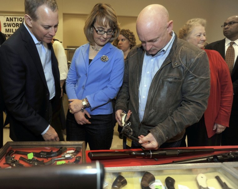 New York Attorney General Eric Schneiderman, left, former Arizona congresswoman Gabrielle Giffords, center, and her husband Mark Kelly tour the New EastCoast Arms Collectors Associates arms fair in Saratoga Springs, N.Y. on Oct. 13. Kelly looks at an antique revolver.