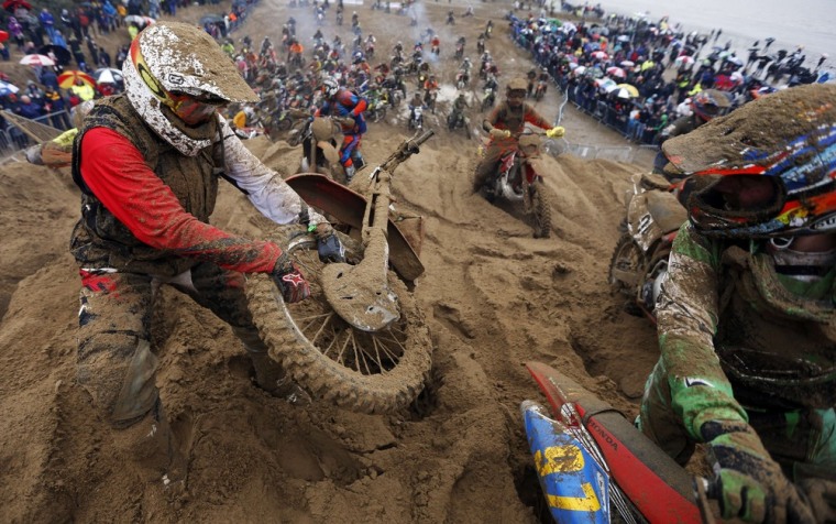 A rider tries to pull his motorcycle out of the sand on dune 18.