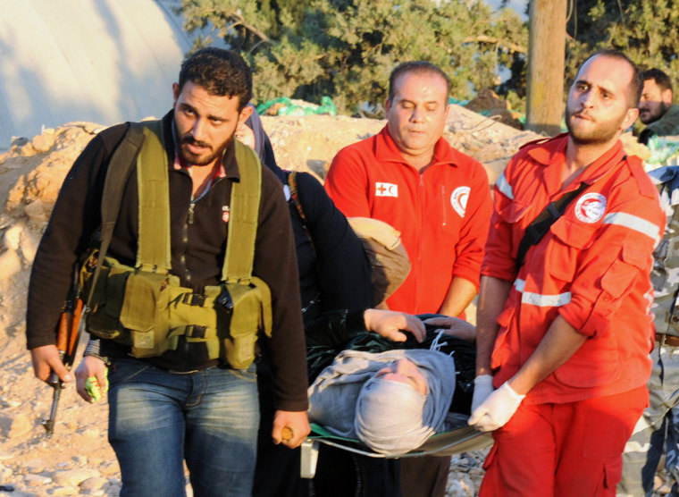 A photo released by the official Syrian Arab News Agency on Saturday shows a fighter and volunteers of Syria's Red Crescent carrying a woman on a stretcher during the evacuation of Syrians from a Damascus suburb under siege.-
