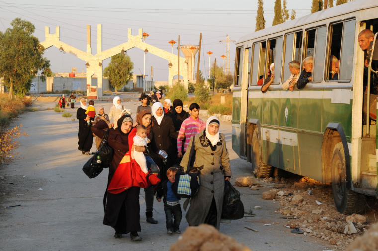 A photo released by the official Syrian Arab News Agency on Saturday shows Syrian women and children arriving to be evacuated by Syria's Red Crescent from a Damascus suburb under siege.