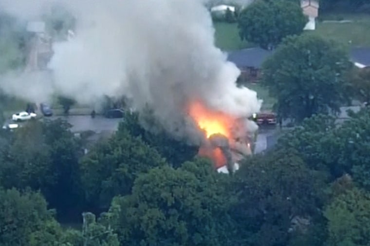 Flames engulf a house in Memphis, Tenn., where a man who shot two police officers was believed to be barricaded Tuesday night.