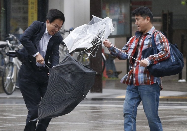 Men react as they struggle against a strong wind and rain caused by approaching Typhoon Wipha at a business district in Tokyo, on Oct. 16.