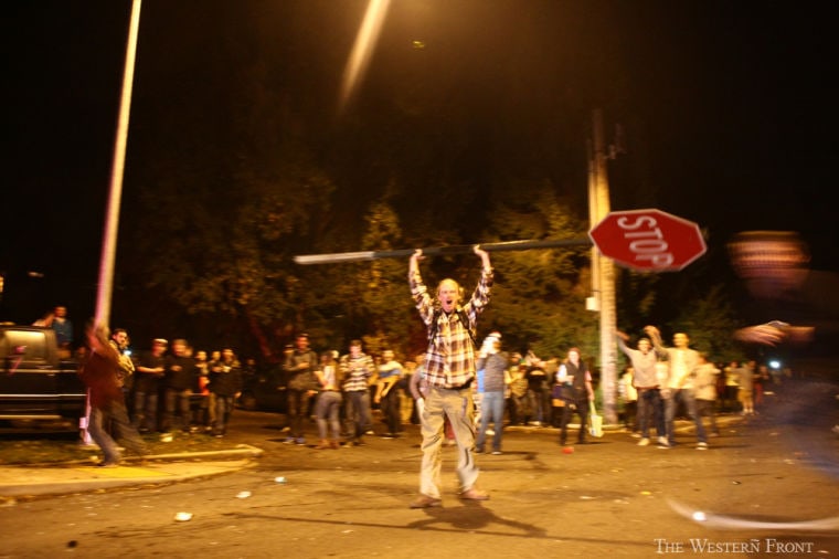 A man holds a stop sign on Saturday night in Bellingham, Wash. The Western Front website said video shows the man picking up the stop sign and hoisting it above his head after another person ripped the sign from its post.