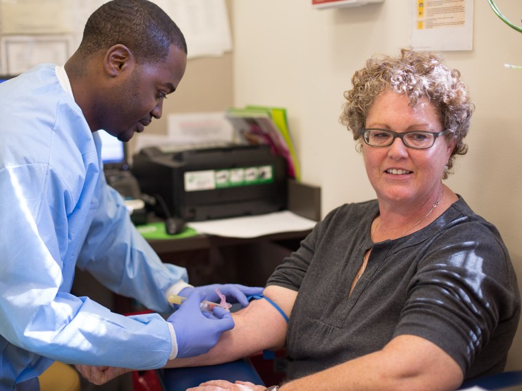 Abdul Muhammad, a group lead trainer for Quest Diagnostics, draws blood from Melanie Mitsui at Mary's Center