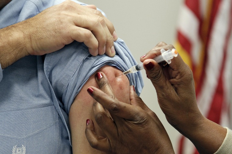 Dr. Paul Byers, deputy state Epidemiologist for the Mississippi Department of Health left, is given an intramuscular shot of flu vaccine Wednesday, Oc...
