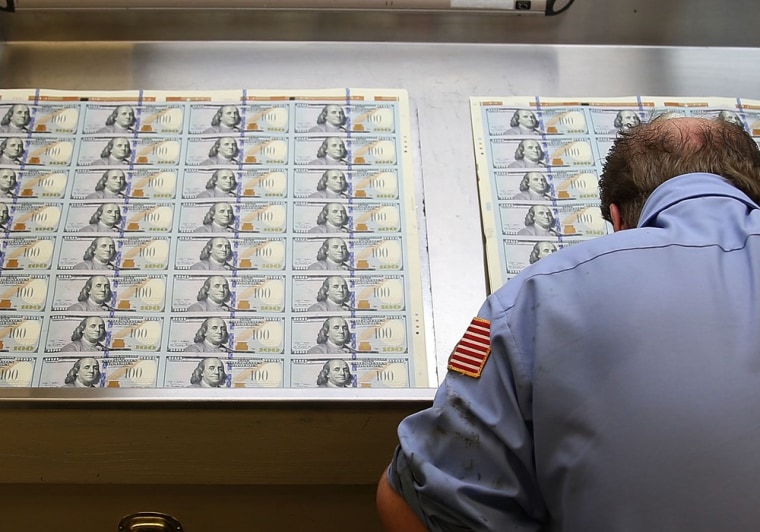 A worker inspects newly redesigned $100 notes during the printing process at the Bureau of Engraving and Printing on May 20, 2013, in Washington, D.C.