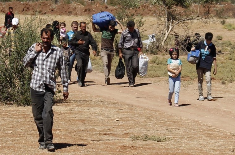 Refugees carry their belongings as they cross from into Turkey near the town of Azaz in Syria.