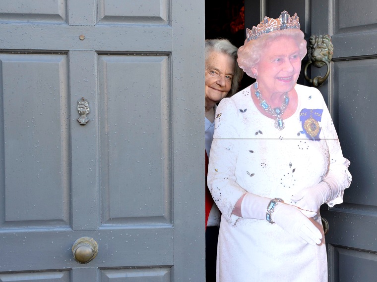 Image: Margaret Tyler poses next to a cutout of a life-size figure of Britain's Queen Elizabeth  II at the front door of her house in London.
