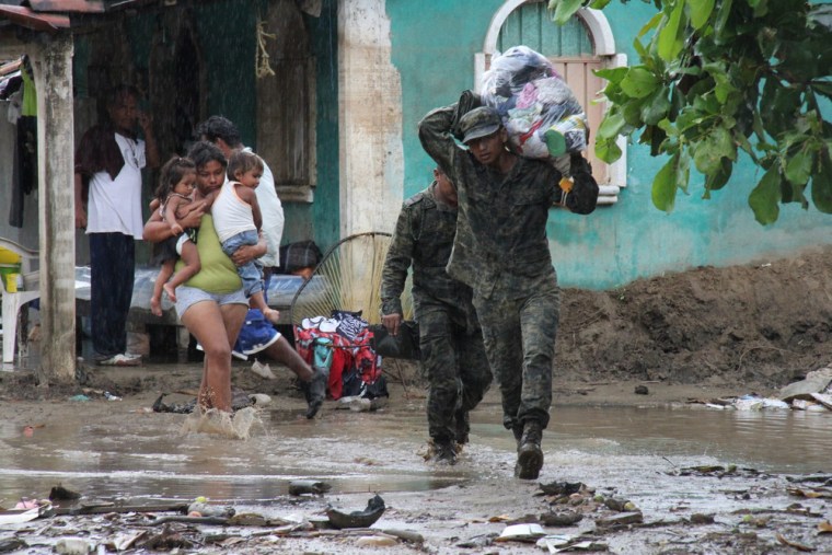 A member of the Mexican army carries the luggage of a family being evacuated from their home in Costa Grande, Guerrero state, on Monday.