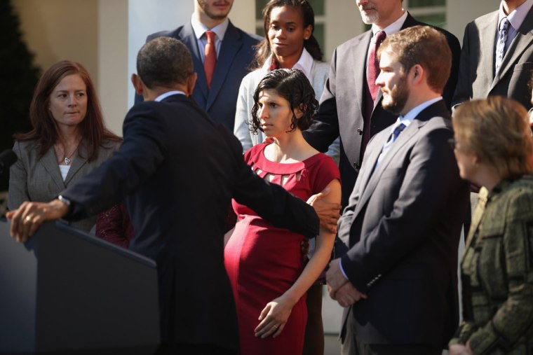 President Barack Obama assists a woman who became dizzy during his remarks about the Affordable Care Act in the Rose Garden of the White House on Oct. 21, 2013.