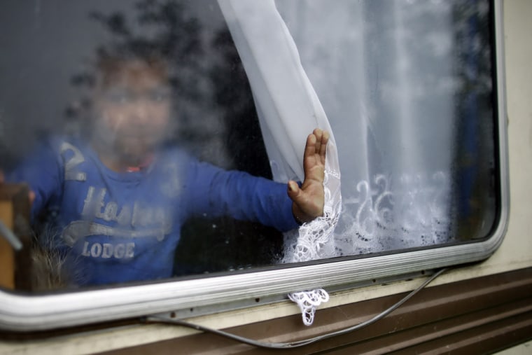 A Roma child is seen at a window of a caravan at an encampment of Roma families in Triel-sur-Seine, near Paris.