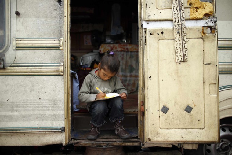 A girl draws at the door of a caravan at an encampment of Roma families in Triel-sur-Seine.